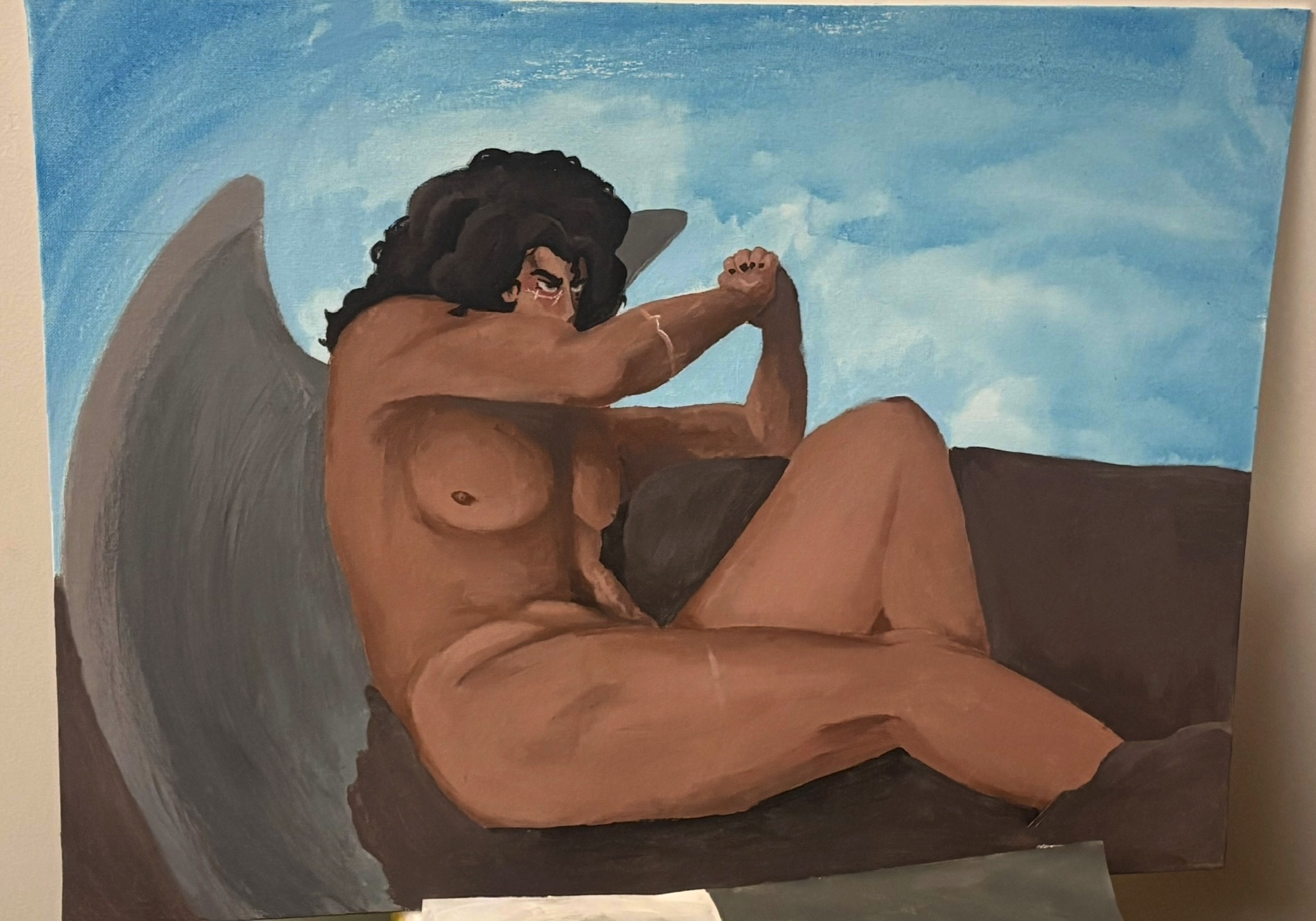 A painting of a dark skinned young man with his arm covering the lower half of his face. He is muscular and has a few scars. His hair is black and long, curling past his shoulders. He has grey wings which obscure part of the background, which is a simple blue sky and neutral brown rocks.